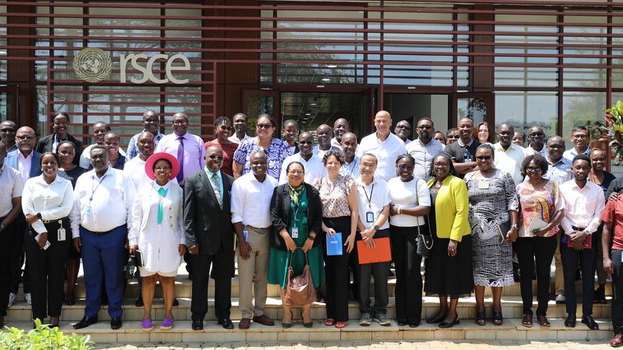 A group of people standing on steps in front of a building with the word "RSCE" behind them. They are smiling.