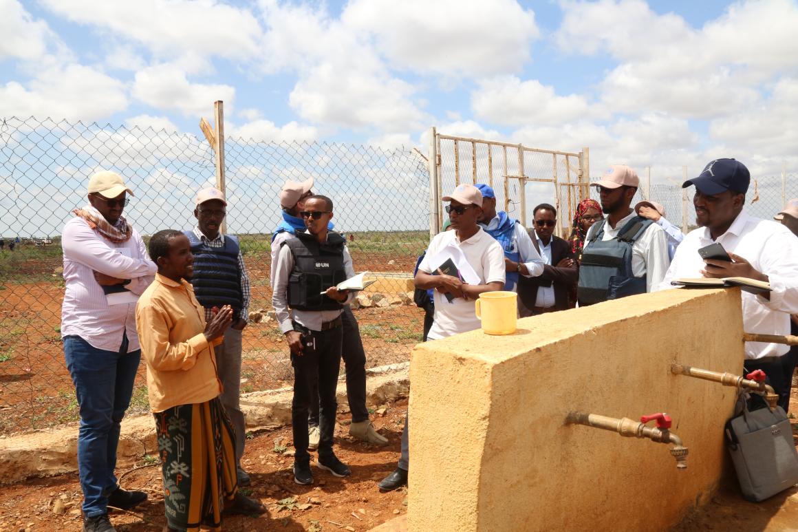 A photo of a delegation from Somali Joint Fund and representatives from the federal government of Somalia and Southwest State receive a briefing from the caretaker of Saameynta Pilot Irrigation Project in Barwaqo settlement in Baidoa